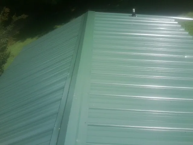New green metal panels meeting at the ridge of a roof — Flat Roof Repair work by our crew in Bowman