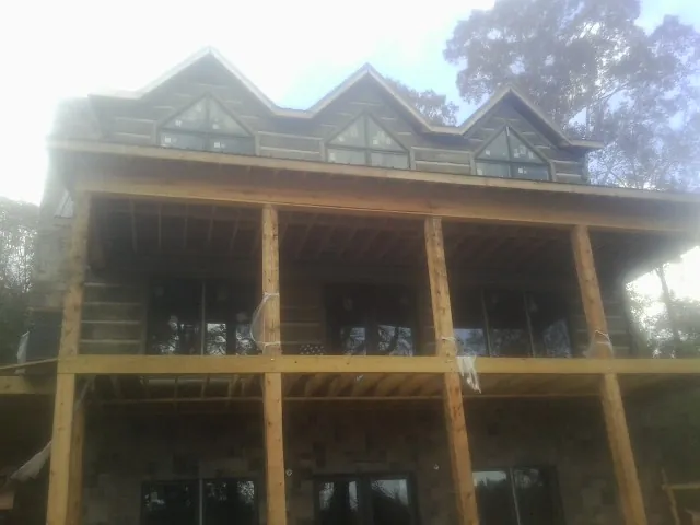 Dormers and porch framing on a large log home under construction — Roof Coating work by our crew in Bowman