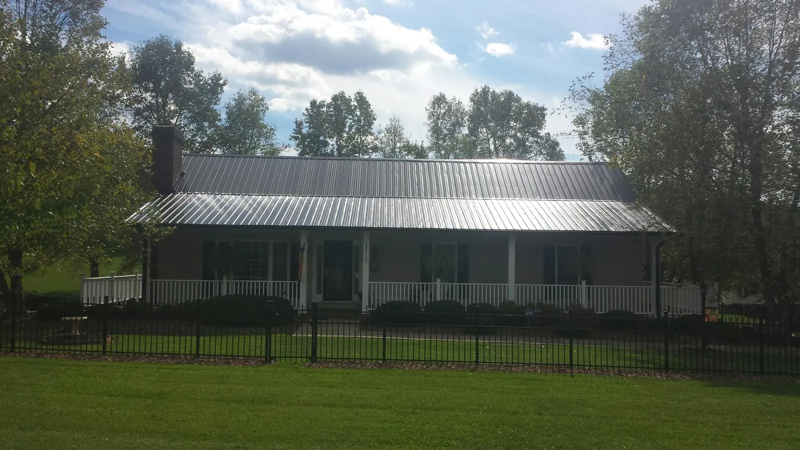 Gray metal roof on a brick ranch with a full width front porch — Gutter Guard Installation work by our crew in Bowman